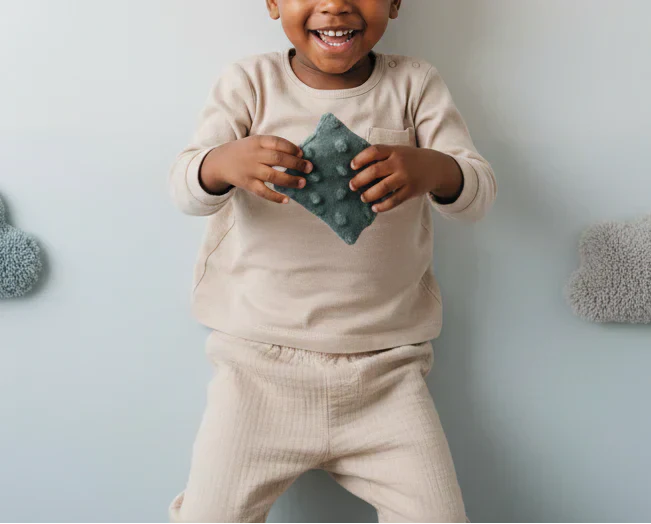 Apaizdoudou vert tenu par un enfant souriant et apaisé 